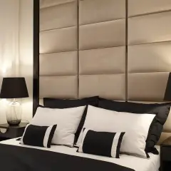 Elegancka sypialnia w stylu hotelowym. Miękkie, pikowane wezgłowie, czarno-biała pościel i stylowe lampki nocne tworzą luksusową atmosferę.