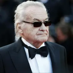 Jerzy Skolimowski w smokingu i okularach przeciwsłonecznych, ikona polskiego kina.