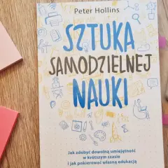 Książka "Sztuka samodzielnej nauki" leży obok różowych karteczek i zakreślaczy. Idealna do nauki angielskiego.