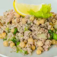 Insalata di ceci e tonno, fresca e saporita, guarnita con limone e sedano.