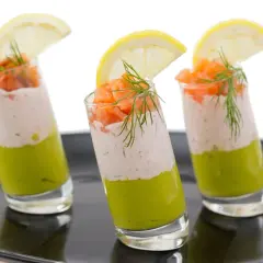 Trois verrines charcuterie : avocat, crème et saumon fumé, garnies d'aneth et d'une tranche de citron.
