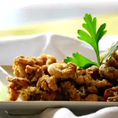 Camagroc crujiente en un plato blanco, decorado con perejil fresco. ¡Un bocado delicioso!