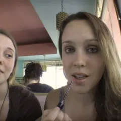 Dwie dziewczyny w kawiarni. Jedna maluje usta, druga patrzy w bok. Scena z filmu "Megan is missing".