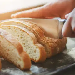 Krojony chleb na desce, gotowy, by dowiedzieć się, jak podgrzać chleb w piekarniku.