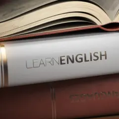 Stos książek, na wierzchu otwarta, z napisem "LEARN ENGLISH" na białej okładce. Idealne książki po angielsku do nauki.