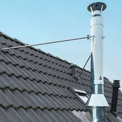 Edelstahl-Ofenrohre verbinden sich auf einem dunklen Ziegeldach. Ein Metallarm stützt das glänzende Rohr.