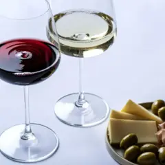 Dwa kieliszki wina, czerwonego i białego, z deską serów, oliwek i szynki. Wino właściwości są doceniane przez koneserów.