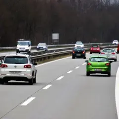Ruch na autostradzie. Kierowca zielonego auta zastanawia się, jaki mandat za wymuszenie pierwszeństwa, gdyby to zrobił.