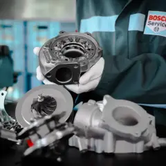 Mechanik w białych rękawiczkach prezentuje części turbiny w samochodzie.