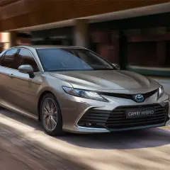 Elegancka, brązowa Toyota Camry Hybrid w ruchu. Poznaj jej imponujące toyota camry wymiary, idealne do miasta i na trasy.
