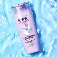 Botella de champú Elvive Hyaluron Plump sobre fondo azul con burbujas, ideal para pelo seco.