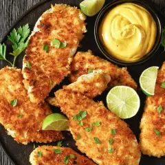 Chrupiący kotlet z piersi kurczaka, podany z sosem i limonką. Idealny na szybki obiad.