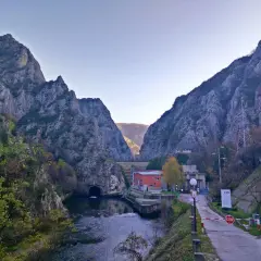 Wąwóz Matka, z potężnymi górami po bokach, rzeką i tunelem. Droga prowadzi do zapory.