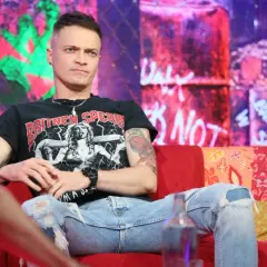 Nocny kochanek wokalista w czarnej koszulce z Britney Spears, siedzi na kanapie w podartych jeansach.