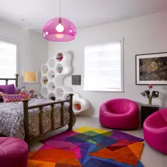 Habitación moderna y colorida, ideal para decorar con estilo. Cama con dosel, estantería blanca escultural, alfombra geométrica y sillones fucsia.