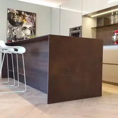 Moderno montaggio cucina con isola centrale in legno scuro, sgabelli bianchi e quadro artistico.