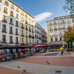 Piazza vivace con caffè all'aperto e persone che passeggiano, un'atmosfera tipica della zona gay di Madrid.