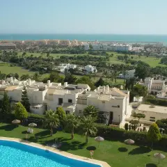 Vista aérea de Almerimar: complejos residenciales blancos, campo de golf verde y el mar azul. Ideal para saber qué ver en Almerimar.