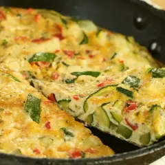 Pyszny omlet z cukinii z kawałkami papryki, podany na patelni. Idealny na śniadanie lub lekki obiad.
