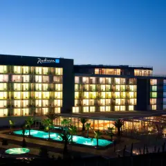 Hotel Radisson Blu Split nocą, z podświetlonymi oknami, basenami i palmami.