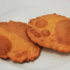 Dos tortos asturianos dorados y crujientes sobre un plato blanco.
