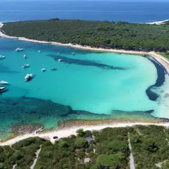 Widok z lotu ptaka na turkusową zatokę z łodziami, otoczoną zielonymi lasami. To musi być najpiękniejsza plaża w Chorwacji!