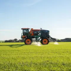 Pulvérisateur agricole Stara 3000 en action, assurant le nettoyage et la protection des cultures dans un champ verdoyant sous un ciel bleu.