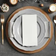 Elegancko ułożone sztućce: widelec po lewej, nóż i łyżka po prawej. Na talerzu biała kartka, idealna na menu.