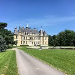 Château majestueux sous un ciel bleu, avec une allée menant à l'entrée. Un lieu idéal pour déguster un champagne Le Gallais.