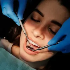 Dentysta bada zęby pacjentki, szukając oznak problemów, takich jak halitoza objawy.