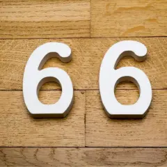 Białe cyfry 66 na drewnianym tle.
