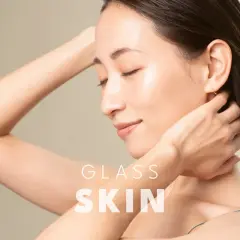 Kobieta z idealną, lśniącą cerą typu "glass skin", z dłońmi na karku.