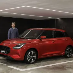Hombre posando junto a un Suzuki Swift rojo brillante, listo para su prueba.