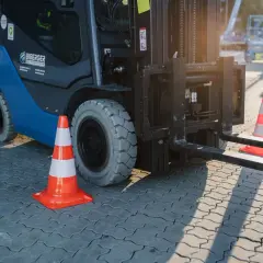 Ein Gabelstapler steht bereit, um zu stapler fahren. Orangefarbene Verkehrskegel markieren den Bereich.