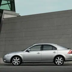 Srebrny Ford Mondeo MK3 2.0 TDCI stoi na tle nowoczesnego budynku z kamienną fasadą.