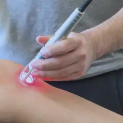 Un terapista applica un laser su un ginocchio. Scopri i laserterapia costi per il tuo benessere.