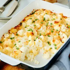 Ein goldbrauner Blumenkohlauflauf mit Käse überbacken und mit Schnittlauch bestreut, bereit zum Servieren.