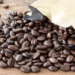 Chicchi di caffè Arabica tostati, con un sacchetto dorato aperto da cui fuoriescono. Il caffè Arabica, noto per il suo aroma delicato, è il significato di un'esperienza gustativa raffinata.