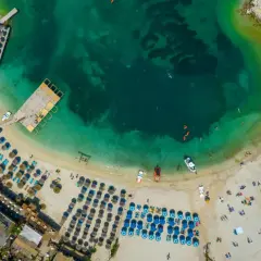 Rajska plaża z turkusową wodą, leżakami i parasolami. Idealne miejsce, by zastanowić się, gdzie do Albanii na wakacje.