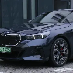 Eleganckie bmw serii 5 w ciemnym kolorze, z charakterystycznym grillem i sportowymi felgami, zaparkowane na brukowanej nawierzchni.