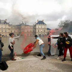 Protestujący z racami i dmuchanym obiektem przed budynkiem w Paryżu.