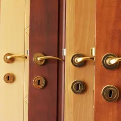 Plusieurs portes en bois aux teintes variées, chacune ornée d'une poignée dorée. L'idée de peindre une porte en bois prend tout son sens devant cette diversité.
