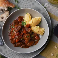 Herzhaftes Spezzatino di manzo mit cremigem Polenta, dazu ein Glas Rotwein und rustikales Brot.