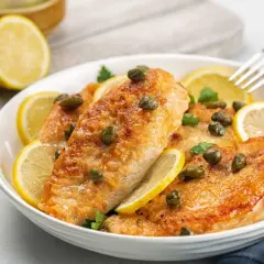 Délicieux poulet au citron, garni de câpres et de rondelles de citron frais, prêt à être dégusté.