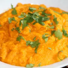 Purée de carotte onctueuse, garnie de feuilles de coriandre fraîche. Un délice orangé et savoureux.