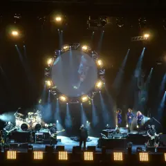 Koncert Australian Pink Floyd z okrągłym ekranem i wokalistami na scenie.