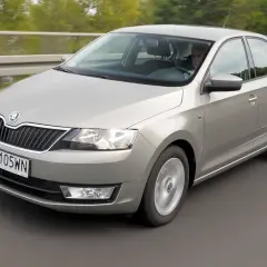 Srebrny Skoda Rapid 2018 jedzie po drodze, za kierownicą siedzi mężczyzna.