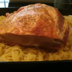 Rohes Schweinefleisch mit Gewürzen liegt auf Sauerkraut in einer Bratreine. Bereit zum Kochen.