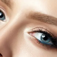 Blonde Haarfarbe betont blaue Augen. Nahaufnahme eines weiblichen Auges mit blauem Eyeliner und goldenem Lidschatten.