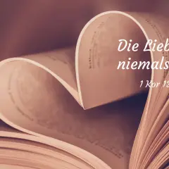 Ein aufgeschlagenes Buch formt ein Herz. Darauf steht: "Die Liebe hört niemals auf. 1 Kor 13,8". Bibelverse über die Liebe für Partner.